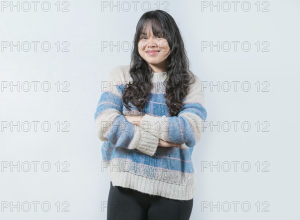 Young Asian female with crossed arms on white background. Portrait of beautiful and smiling Asian woman on isolated background