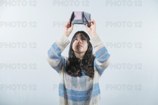 Young woman shaking her empty wallet. Worried girl with no money holding empty wallet, isolated