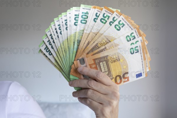 Human hand with several 50 and 100 euro banknotes