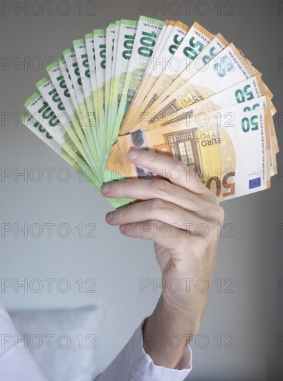 Human hand with several 50 and 100 euro banknotes