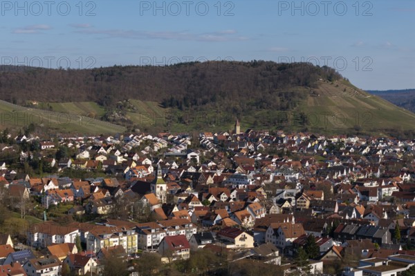 View of city with red roofs, surrounding green hills and clear blue sky, Korb im Rems Valley, Baden-Württemberg, Germany