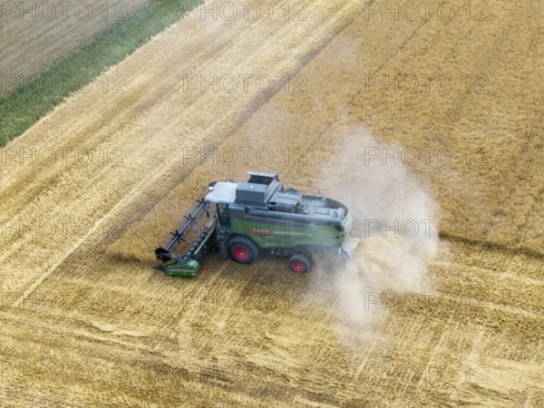 A combine harvester works in a cornfield and stirs up dust during harvesting, basket in Remstal, Baden-Württemberg, Germany