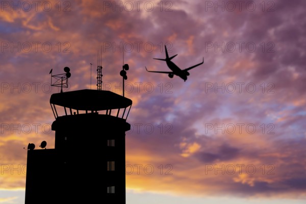 Air traffic control tower at airport as airplane takes off