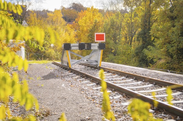 Railway track ends with a barrier surrounded by autumnal nature, ZOB Calw, Hermann Hessebahn, Calw, Germany