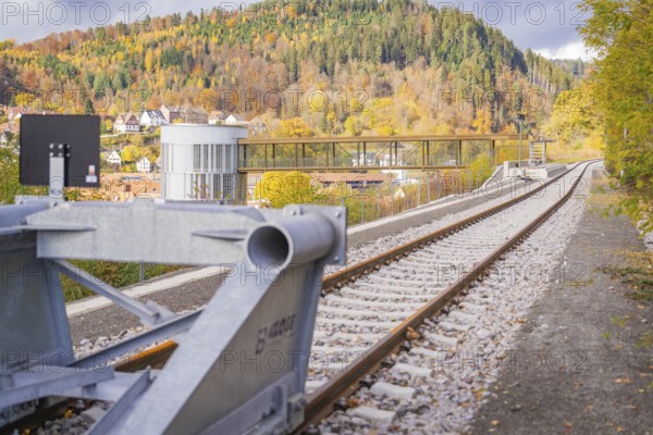Tracks along a modern building with a bridge against an autumn mountain backdrop, ZOB Calw, Hermann Hessebahn, Calw, Germany