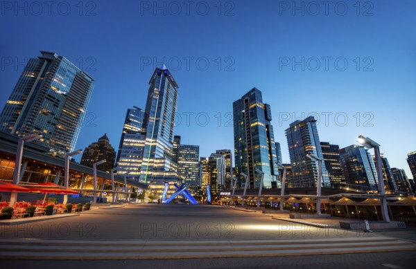 Illuminated skyscrapers on the promenade in the evening, Olympic Cauldron Statue, Jack Poole Plaza Square, Blue Hour, Coal Harbour, Vancouver, British Columbia, Canada