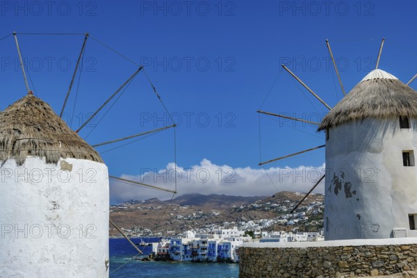 Mykonos, Cyclades, Greece - The six sixteenth-century windmills, lined up on a hill above Mykonos Town, Mykonos Chora, are the island's landmark. At the back, right by the sea, are the colorful houses of Little Venice. Mykonos is part of the Cyclades archipelago in the Aegean Sea