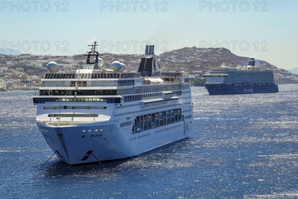 Mykonos, Cyclades, Greece - Cruise ships MEIN SCHIFF 5 and MSC LIRICA are located in the bay off Mykonos City. Old town with windmills. Cruise ships bring tourists to shore