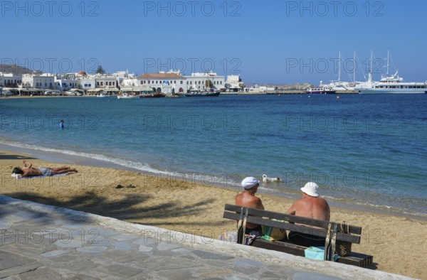 Mykonos, Cyclades, Greece - Tourists and locals like to bathe on the small town beach Paralia Chora Mikonou right at the harbor in the old town of Mykonos Town, Mykonos Chora. Mykonos is part of the Cyclades archipelago