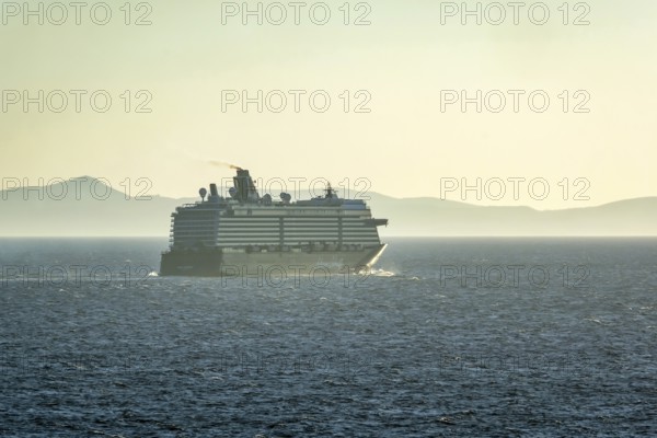 Mykonos, Cyclades, Greece - Cruise ship MEIN SCHIFF 5 sails out of Mykonos harbour bay and leaves behind a dark exhaust cloud