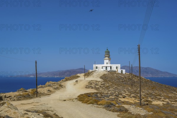 Mykonos, Cyclades, Greece - The Armenistis lighthouse in the north of the island is a landmark and a popular destination for tourists. In the back is the island of Tinos