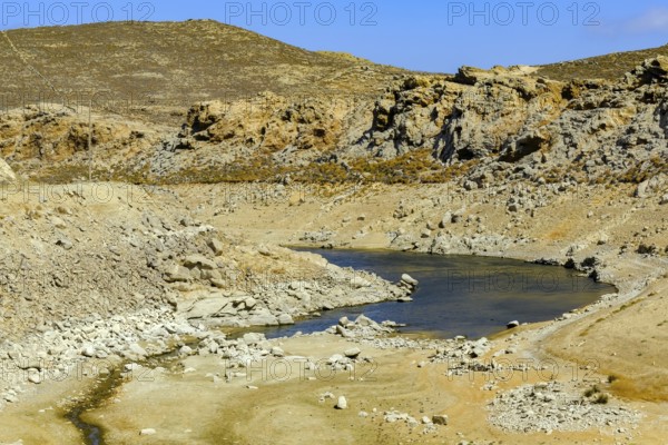 Mykonos, Cyclades, Greece - Dry Fokos Reservoir near Ano Mera. The Mykonos Municipal Water Supply and Sewage Management Company has two dams, Marathi Reservoir and Fokos Reservoir, to supply water to the island. Due to the prolonged drought, both are almost empty and are not being used