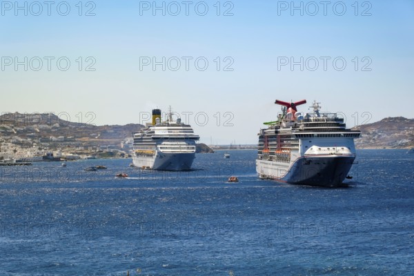Mykonos, Cyclades, Greece - cruise ships CARNIVAL MIRACLE and COSTA FORTUNA are located in the bay off Mykonos City. Old town with windmills. Cruise ships bring tourists to shore
