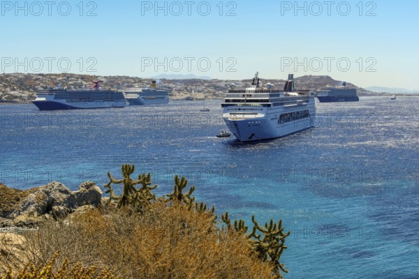 Mykonos, Cyclades, Greece - cruise ships CARNIVAL MIRACLE, COSTA FORTUNA, MEIN SCHIFF 5 and MSC LIRICA are located in the bay off Mykonos Town. Old town with windmills. Cruise ships bring tourists to shore