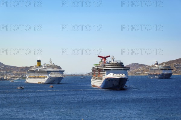 Mykonos, Cyclades, Greece - cruise ships CARNIVAL MIRACLE, COSTA FORTUNA and MEIN SCHIFF 5 are located in the bay off Mykonos Town with a view of the old town with the windmills. Cruise ships bring tourists to shore