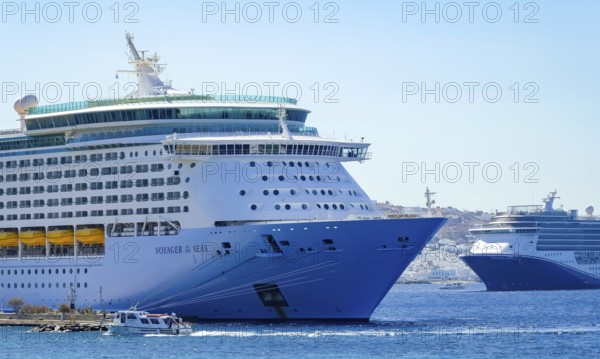 Mykonos, Cyclades, Greece - Voyager of the Seas cruise ship is located in Mykonos New Port. In the back is the old town of Mykonos