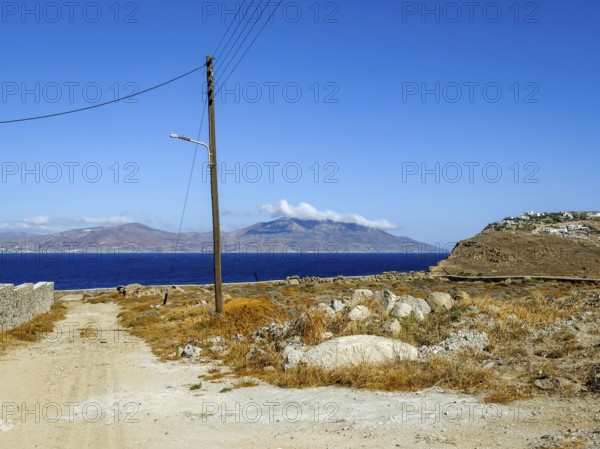 Mykonos, Cyclades, Greece - Barren landscape with street lamp on wooden pole, power pole, telephone pole. In the back is the island of Tinos