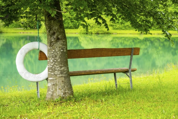 Park bench standing beside beside and with view onto Lake Elisabethsee on a cloudy day in spring, Salzkammergut, Austria