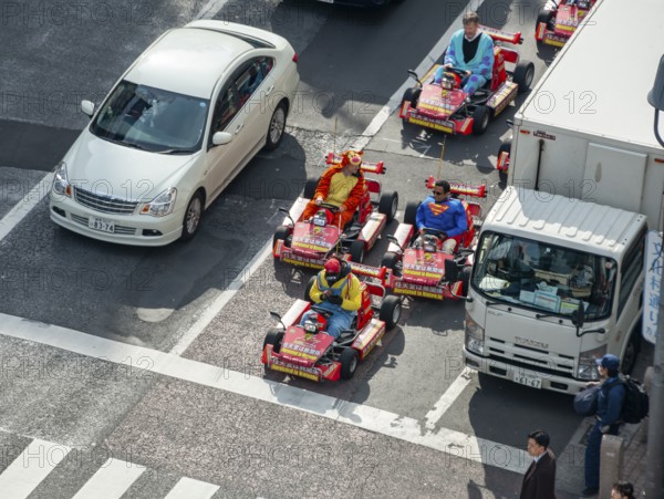 People in costumes ride small go-kart racing cars, Shibuya Crossing, Shibuya, Tokyo
