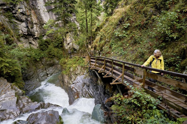 Female hiker standing on wooden walkway, Diosaz mountain river in the gorge, Gorges de la Diosaz, Les Houches, Chamonix-Mont-Blanc, Haute-Savoie, France