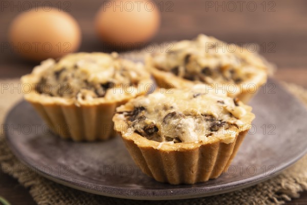 Tartlets with meat and cheese on brown wooden background and linen textile. side view, close up, selective focus