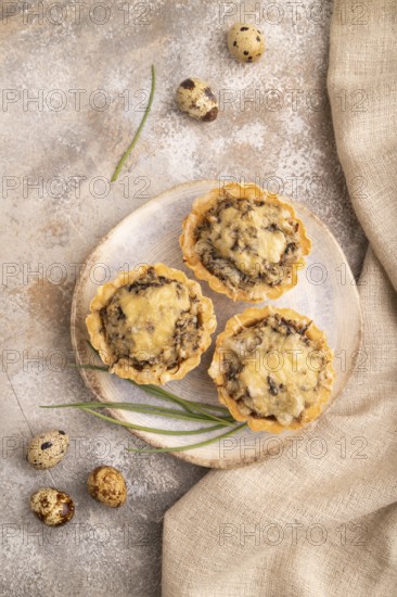 Tartlets with meat and cheese on brown concrete background and linen textile. top view, flat lay, copy space