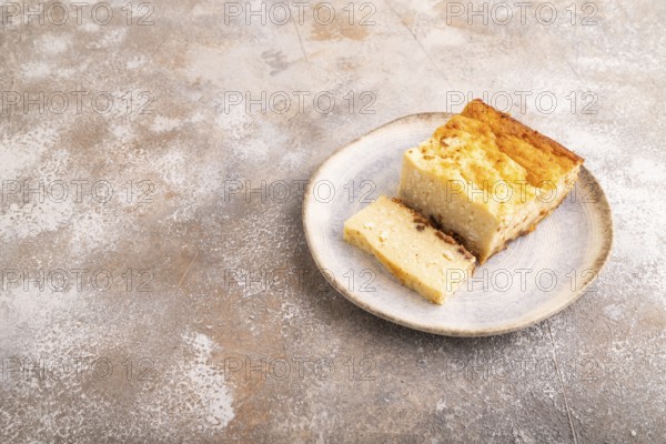 ?ottage cheese ?asserole, Curd cake, with dried apricots and raisins on brown concrete background, side view, copy space, minimalism
