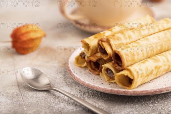 Waffles with caramel on brown concrete background and orange linen textile, cup of coffee, side view, close up, selective focus