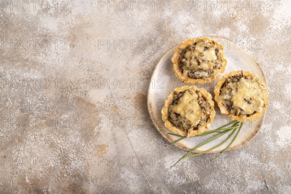 Tartlets with meat and cheese on brown concrete background. top view, flat lay, copy space