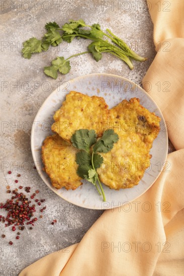 Fried crispy Chicken pancakes on brown concrete background and orange linen textile. top view, flat lay, close up