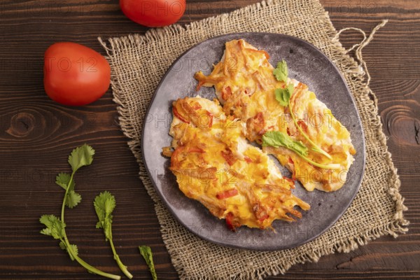 Baked chicken meat with cheese and tomatoes on brown wooden background and linen textile. top view, flat lay, copy space
