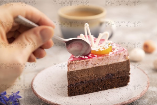 Chocolate cake with hand on brown concrete background, cup of coffee, side view, close up, selective focus