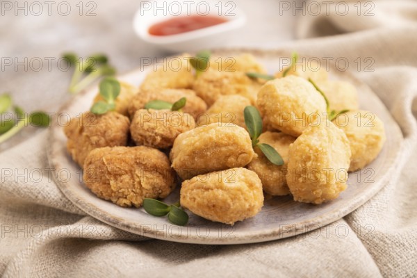 Fried crispy Chicken Nuggets with ketchup, microgreen on brown concrete background and linen textile. side view, close up, selective focus