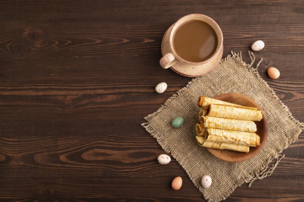 Waffles with caramel on brown wooden background and linen textile, cup of coffee, top view, flat lay, copy space
