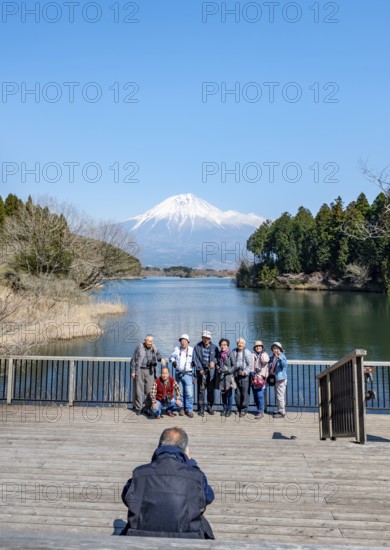 Japanese tour group takes souvenir photo, Fuji-mae observation deck, Mount Fuji volcano and Lake Tanuki, Fujinomiya, Shizuoka, Japan