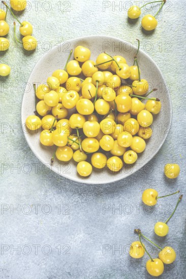 Yellow cherry, cherry berry, scattered on a plate, top view, no people
