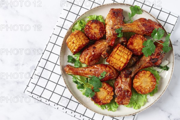 Fried chicken drumsticks, Mexican style, with corn, on a plate, close-up