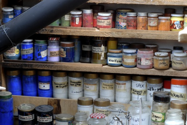 Glasses with various color powders and pigments on a wooden shelf, artist workshop, Zurich, Switzerland