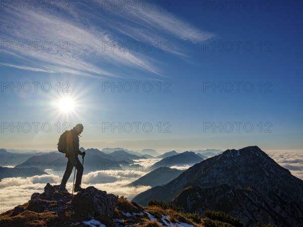 Mountaineer looking at blue-colored silhouette of mountains, fog in the valley, Hochstaufen, Chiemgau Alps, Upper Bavaria, Bavaria, Germany