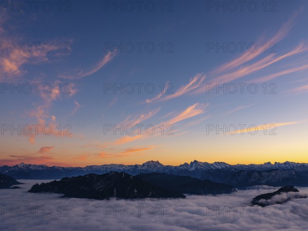 Red-colored plume clouds over the Berchtesgaden Alps at dusk, fog in the valley, Hochstaufen, Chiemgau Alps, Upper Bavaria, Germany