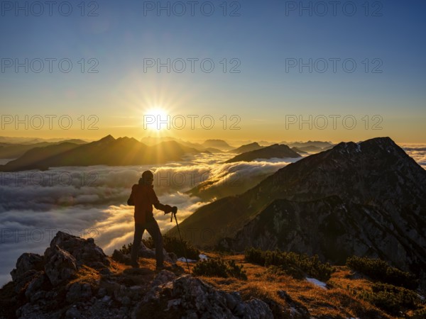 Mountaineer looking at alpine panorama at sunset, fog in the valley, Hochstaufen, Chiemgau Alps, Upper Bavaria, Bavaria, Germany