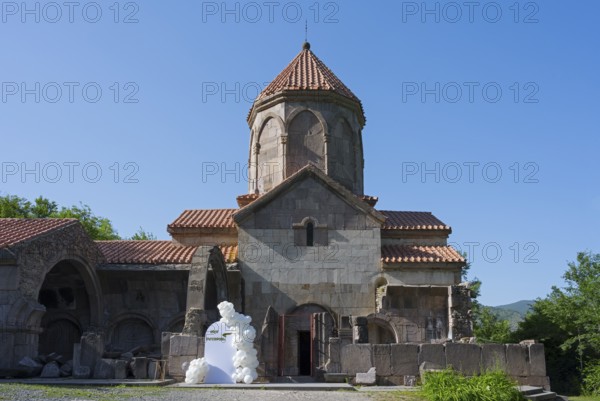 Historic church with tiled roof and blue sky in the background surrounded by greenery, Wahanavank Monastery, Syunik Province, Syunik, Armenia