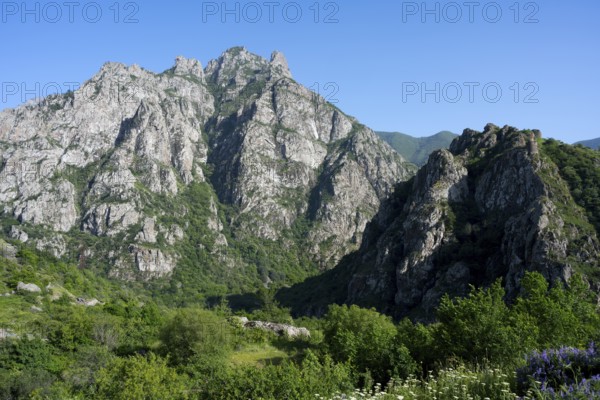 High rocks and mountains with green vegetation under clear summer sky, landscape with Baghaberd fortress, near M2, Syunik province, Syunik, Caucasus, Armenia