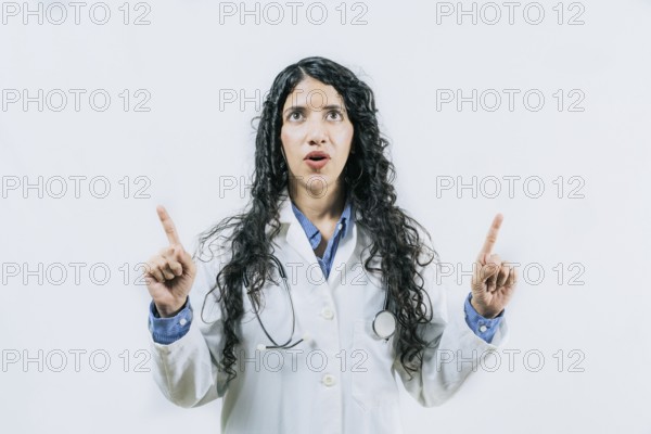 Surprised female doctor pointing up. Young female doctor looking and pointing promotion up isolated