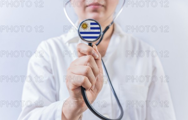 Female doctor holding stethoscope with Uruguay flag. National health system of Uruguay