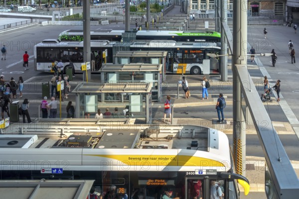 Commuters waiting for transit buses at bus stop of public transport company De Lijn at train station Gent-Sint-Pieters, Ghent, East Flanders, Belgium