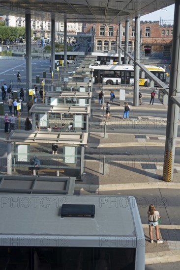 Commuters waiting for transit buses at bus stop of public transport company De Lijn at train station Gent-Sint-Pieters, Ghent, East Flanders, Belgium