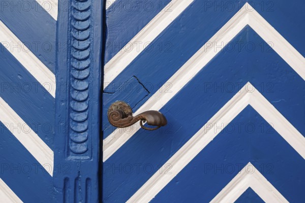 Blue door with white zigzag pattern and antique door knob, Münsterland, North Rhine-Westphalia, Germany