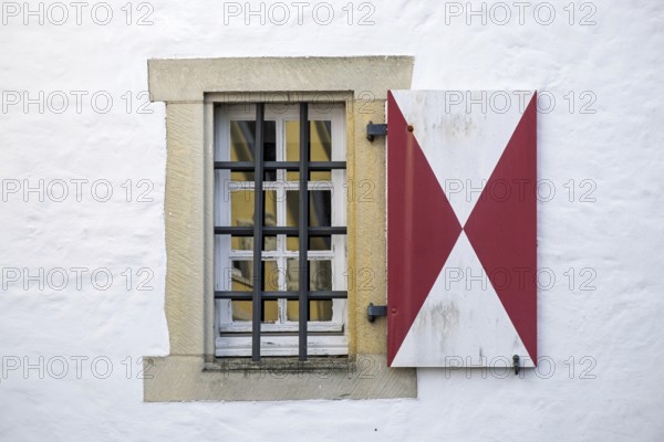 Window with red and white shutters and iron bars in front of a white wall, Münsterland, North Rhine-Westphalia, Germany
