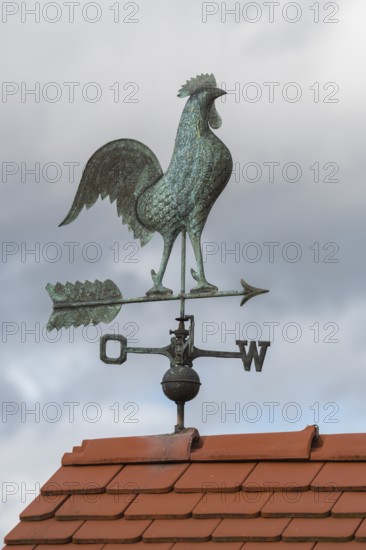 Rooster on metal weather vane on a tiled roof, clouds in the background, Baden-Württemberg, Germany